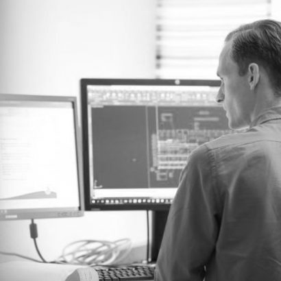 Handsome man sitting in front of computer using software programme CAD