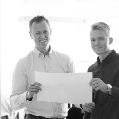 Two smiling young men holding a blueprint together